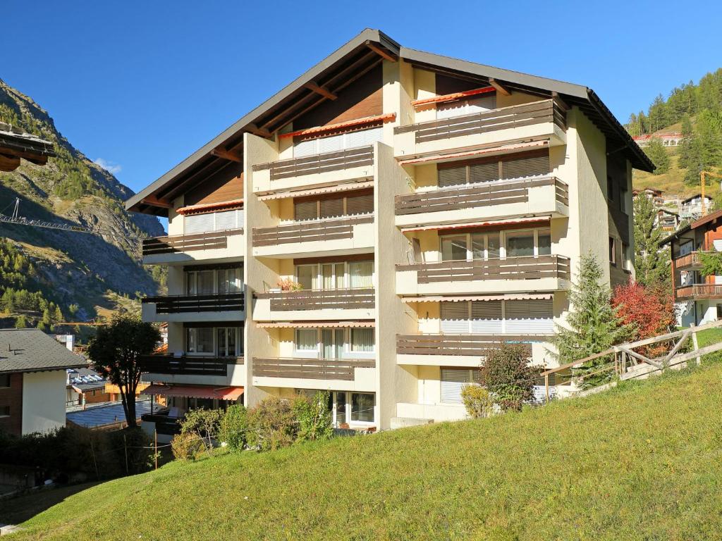 a large apartment building on a hill next to a grassy hill at Apartment Grillon-3 by Interhome in Zermatt