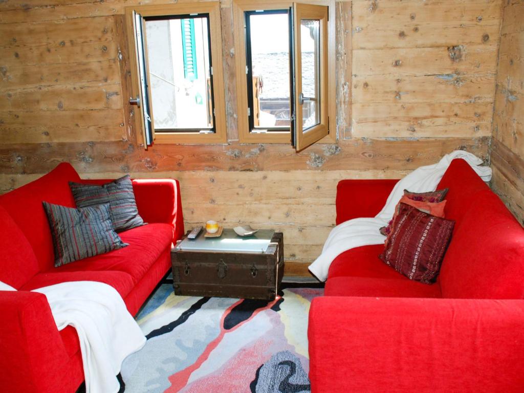 dois sofás vermelhos num quarto com paredes de madeira em Apartment Peppa by Interhome em Chironico