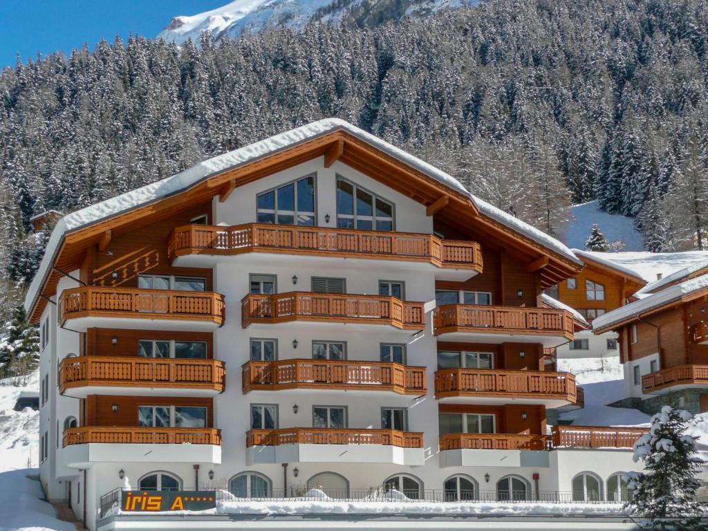 a large apartment building with a snow covered mountain at Studio A01 by Interhome in Leukerbad