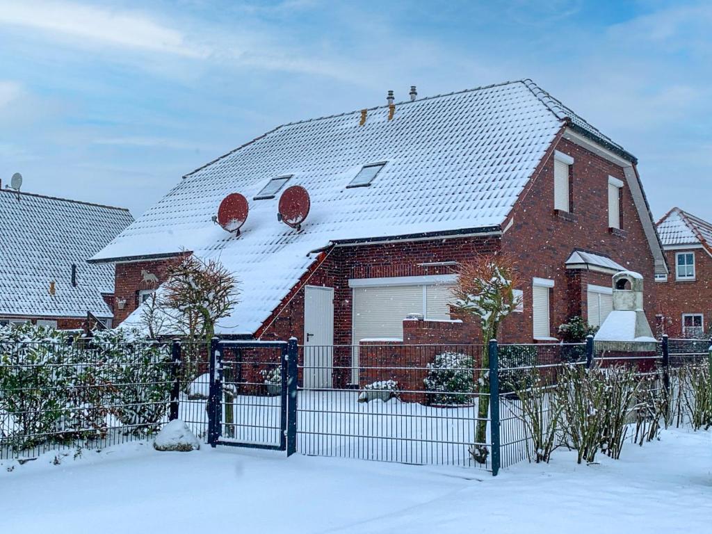 ein rotes Backsteinhaus mit einem schneebedeckten Dach in der Unterkunft Holiday Home Freya by Interhome in Neßmersiel