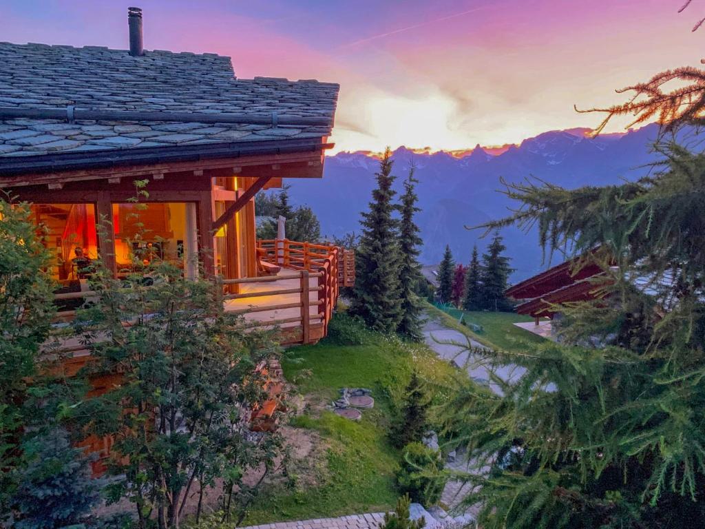 a log cabin in the mountains with the sun setting at Chalet Sebas by Interhome in Nendaz