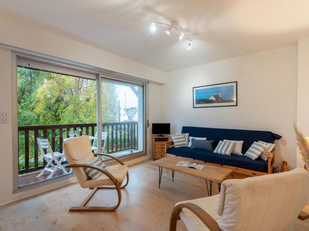 a living room with a blue couch and a balcony at Apartment La Sauvagère-1 by Interhome in Carnac-Plage