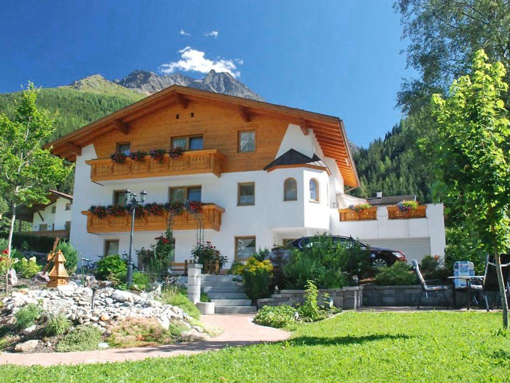 a large white house with a wooden roof at Apartment Stark by Interhome in Pettneu am Arlberg