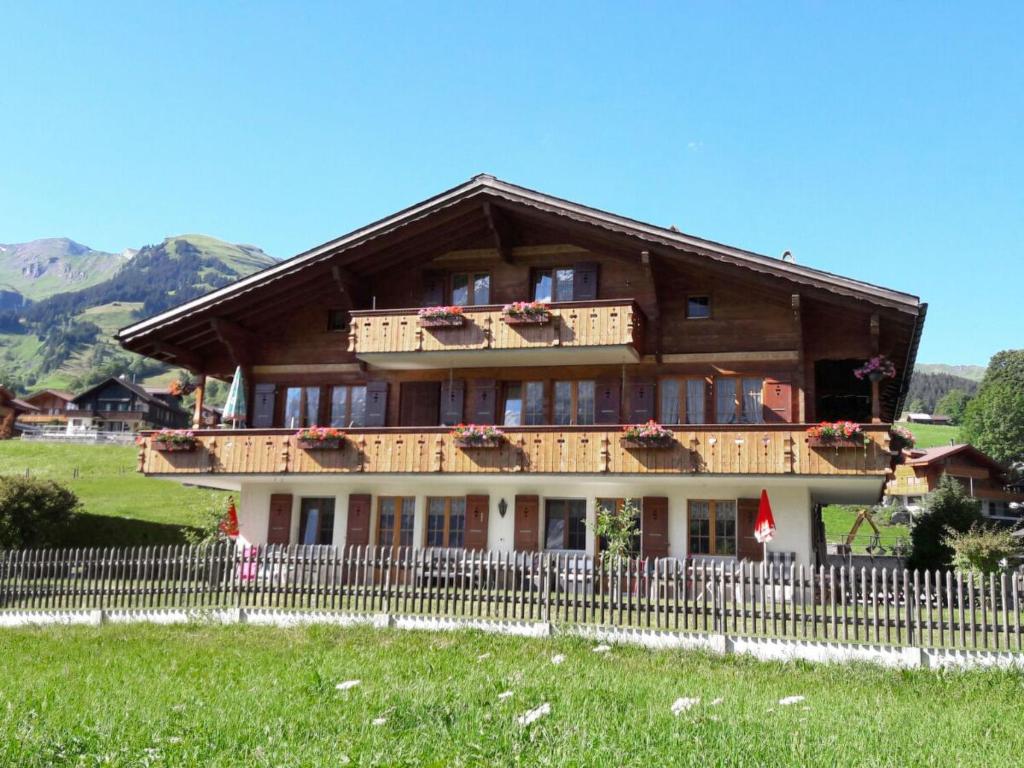 een groot houten huis met een hek ervoor bij Apartment Lohnerhus-1 by Interhome in Grindelwald