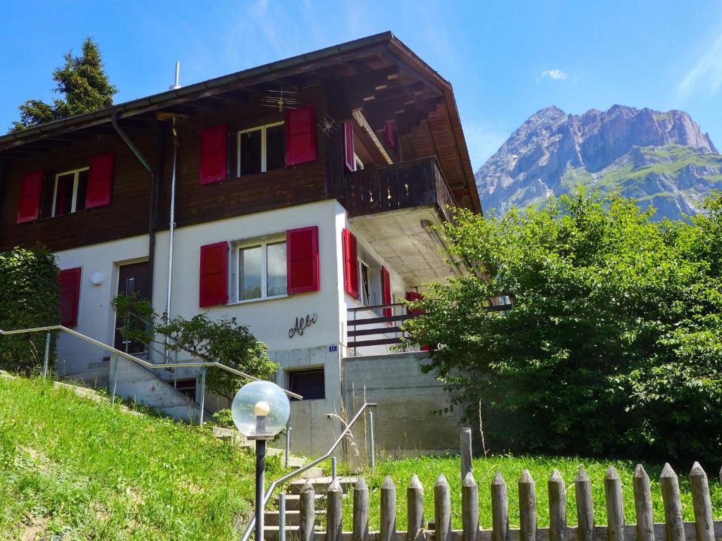 a house with a fence and a mountain in the background at Apartment Chalet Albi by Interhome in Grindelwald