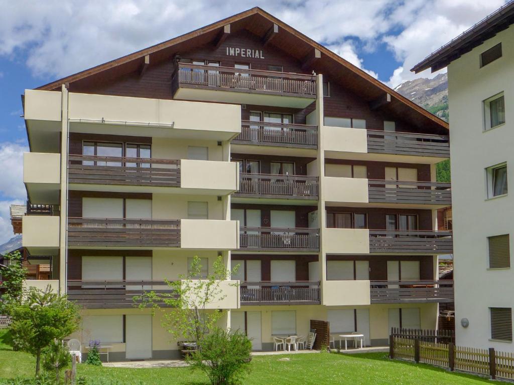 ein großes Apartmenthaus mit Balkonen und Tischen in der Unterkunft Apartment Imperial-10 by Interhome in Zermatt