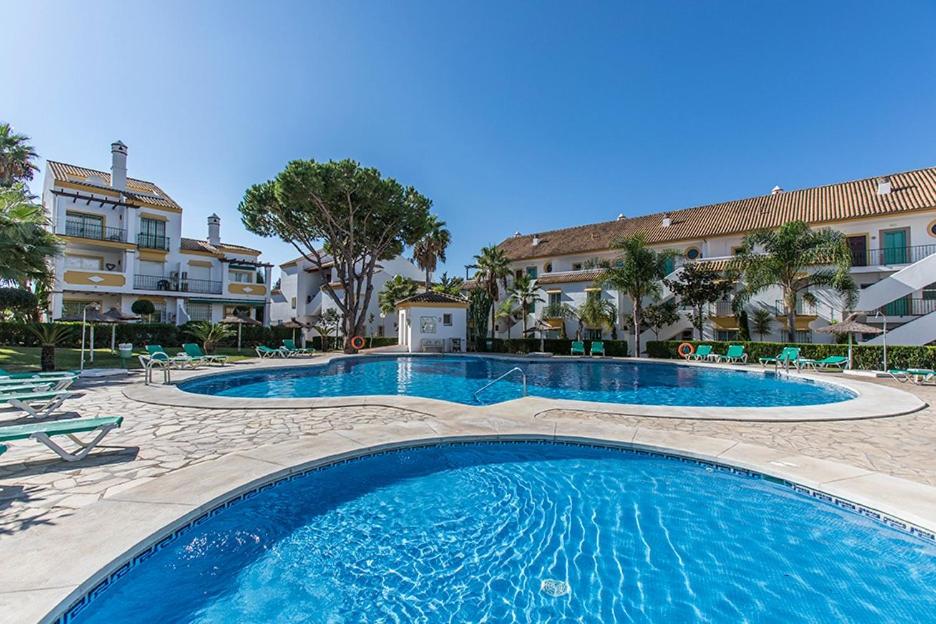 une grande piscine avec des chaises et un bâtiment dans l'établissement Estrelicia II, à Marbella