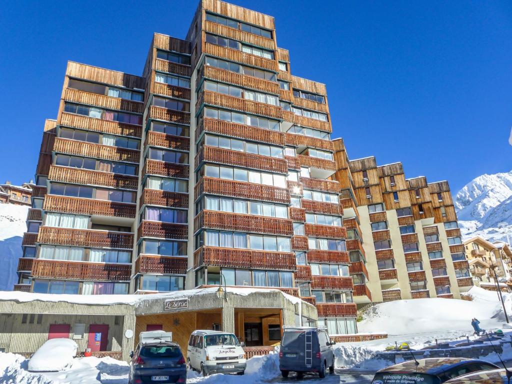 ein großes Gebäude mit Autos im Schnee in der Unterkunft Studio Le Sérac-7 by Interhome in Val Thorens