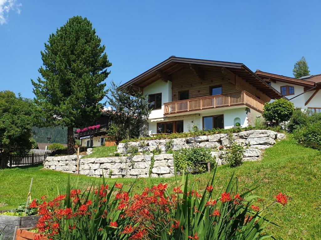 a house on a hill with a stone wall and flowers at Holiday Home Happy by Interhome in Eben im Pongau