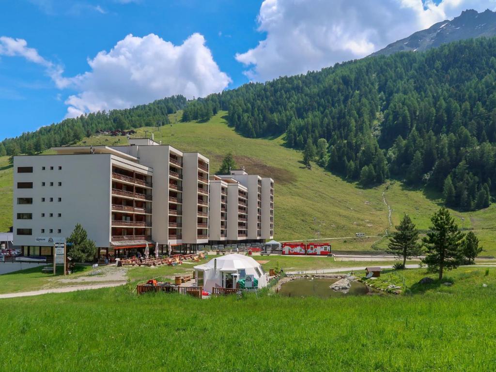 un grand bâtiment sur une colline avec un champ herbeux dans l'établissement Apartment Rosablanche E003A by Interhome, à Siviez