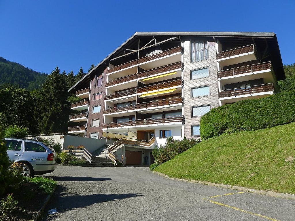 un grand bâtiment avec une voiture garée devant lui dans l'établissement Apartment Schuss 23 by Interhome, à Villars-sur-Ollon