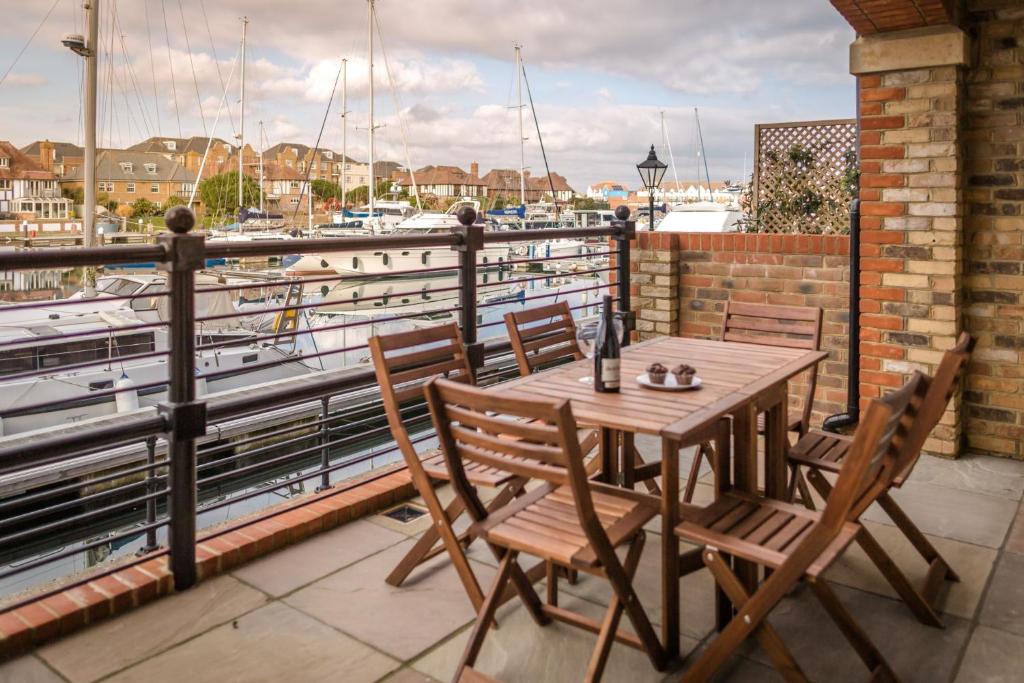 a wooden table and chairs on a balcony with a marina at Harbour Views at Silver Strand in Pevensey