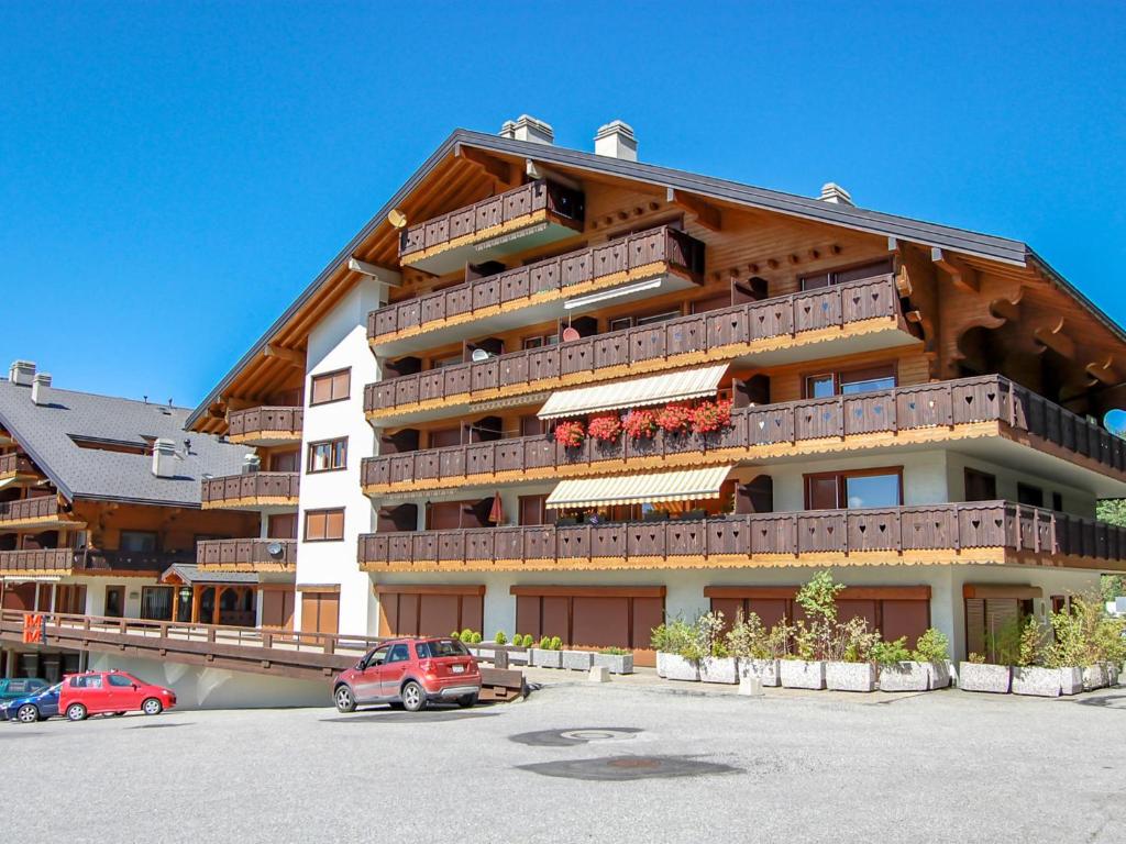 a large building with cars parked in a parking lot at Apartment Lake Placid A7 by Interhome in Nendaz
