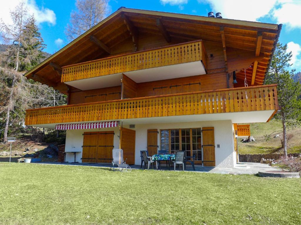 une maison avec un balcon et une table sur une pelouse dans l'établissement Apartment Aiguilles Dorées III-2 by Interhome, à Villars-sur-Ollon