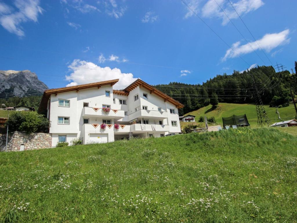 a white building on a hill with a green field at Apartment Susi by Interhome in Flirsch