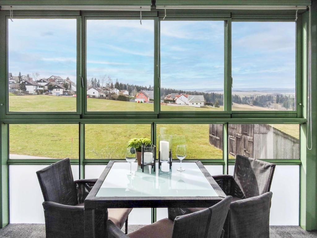 una sala da pranzo con tavolo, sedie e una grande finestra di Apartment Flieder - F 96 by Interhome a Dittishausen