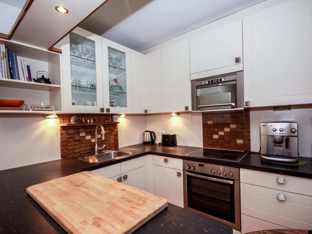 una cocina con armarios blancos y una tabla de cortar de madera en Apartment Tivoli by Interhome en Innsbruck