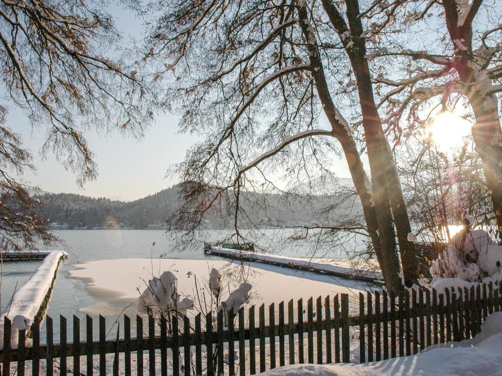 a fence covered in snow next to a lake at Apartment Kleinsee by Interhome in Srejach