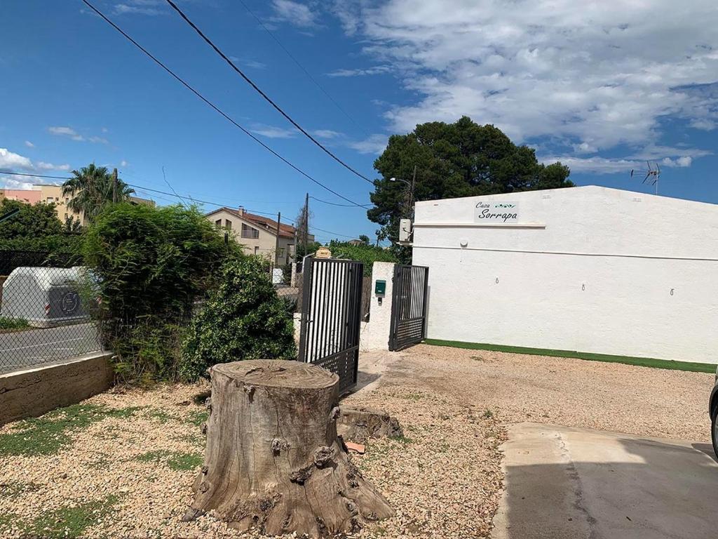 a tree stump in front of a white garage at Estudio "La Cochera de Sorrapa" in Deltebre
