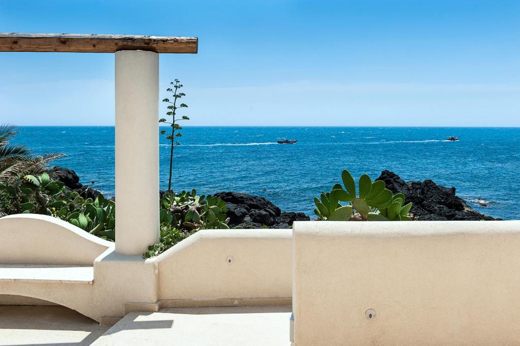 une vue sur l'océan depuis une plage avec un banc dans l'établissement Marina dei Greci - Luxury Villa, à Giardini Naxos