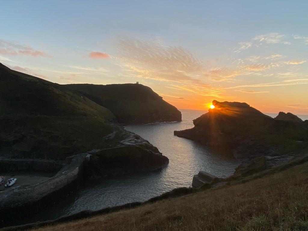 a sunset over a body of water with rocks at Polrunny Farm Seaberry Cottage with a sea view and log burner in Boscastle