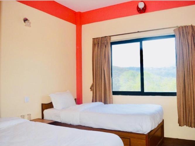 a hotel room with two beds and a window at Panorama Guest House in Nagarkot