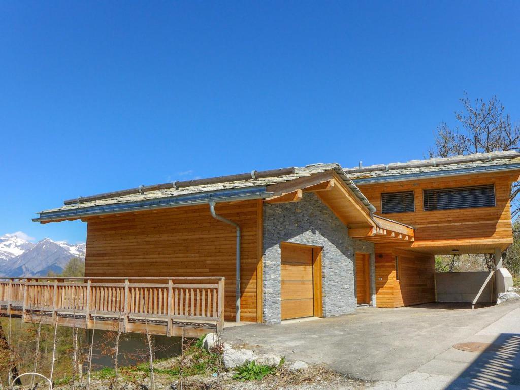 a log home with a deck and mountains in the background at Chalet Woovim 14-3 by Interhome in Nendaz