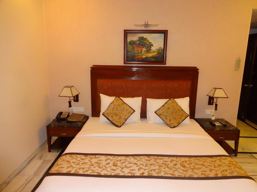 een slaapkamer met een groot bed met 2 nachtkastjes bij Florence Inn in New Delhi