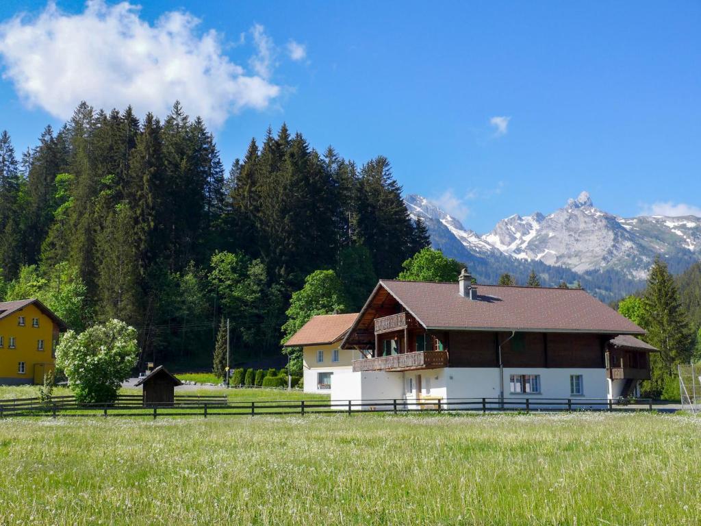 a house in a field with mountains in the background at Apartment Chalet Alte Post by Interhome in Schwenden