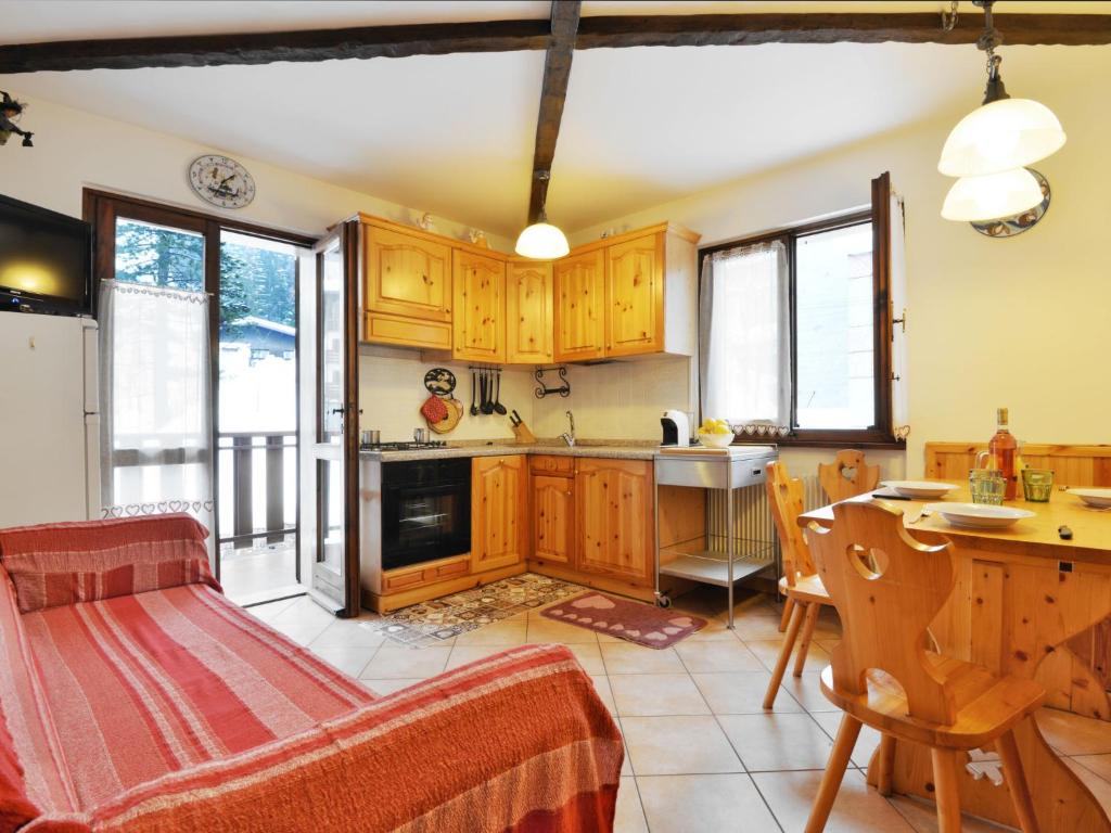 une cuisine avec des placards en bois et une table ainsi qu'une salle à manger dans l'établissement Apartment Al Parco-4 by Interhome, à Canazei