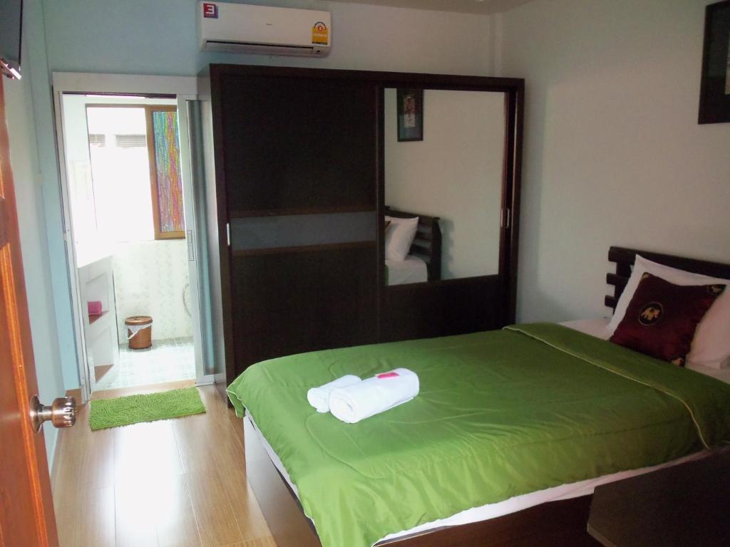 a bedroom with a green bed with a large mirror at Baitong Homestay in Chiang Mai
