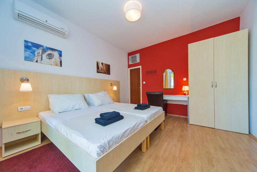 1 dormitorio con cama blanca y pared roja en Apartments Ante en Mlini
