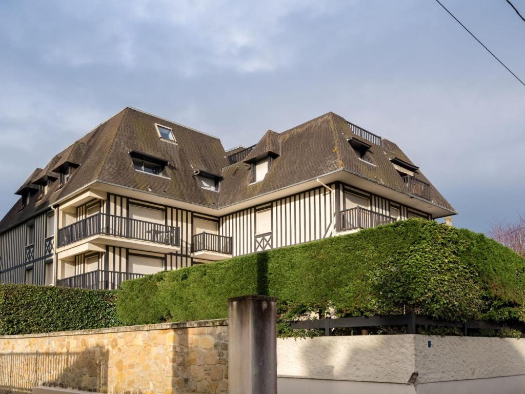 een groot huis met een dak boven een muur bij Apartment Le Capricorne by Interhome in Cabourg