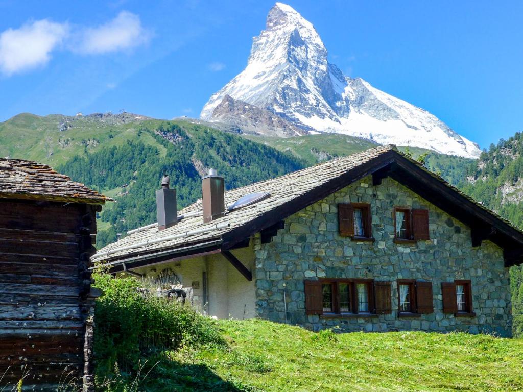 une montagne derrière un bâtiment en pierre avec une maison dans l'établissement Apartment Casa Pia-1 by Interhome, à Zermatt