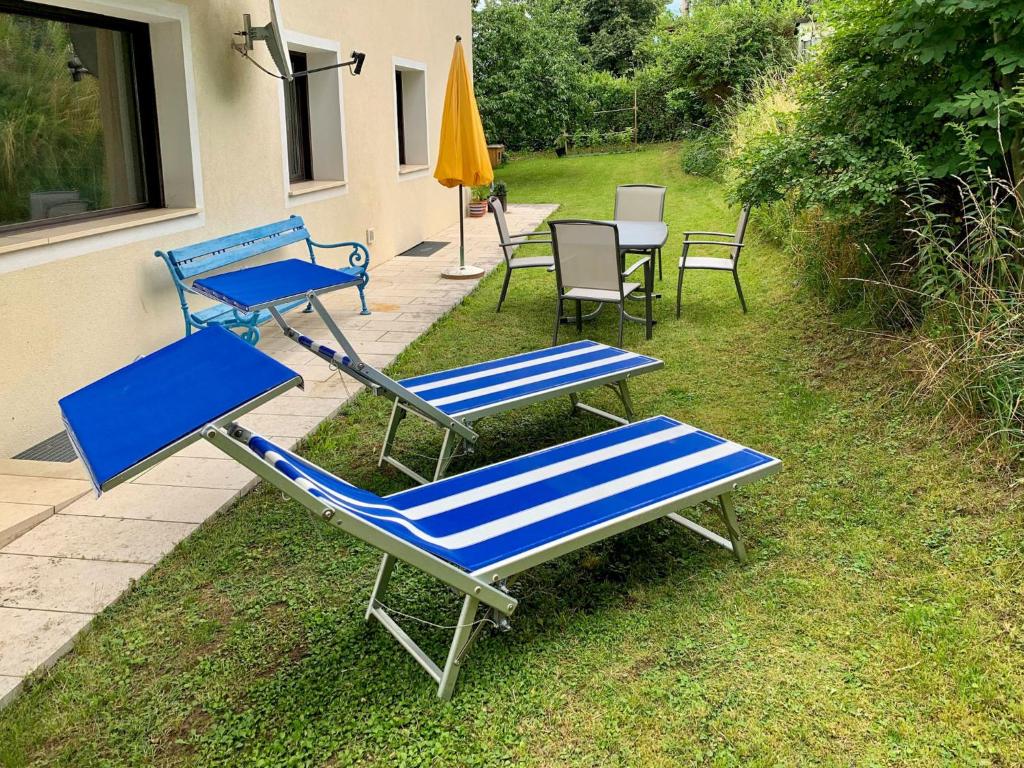 3 chaises longues, une table et des chaises dans la pelouse dans l'établissement Apartment Burgstall by Interhome, à Innsbruck