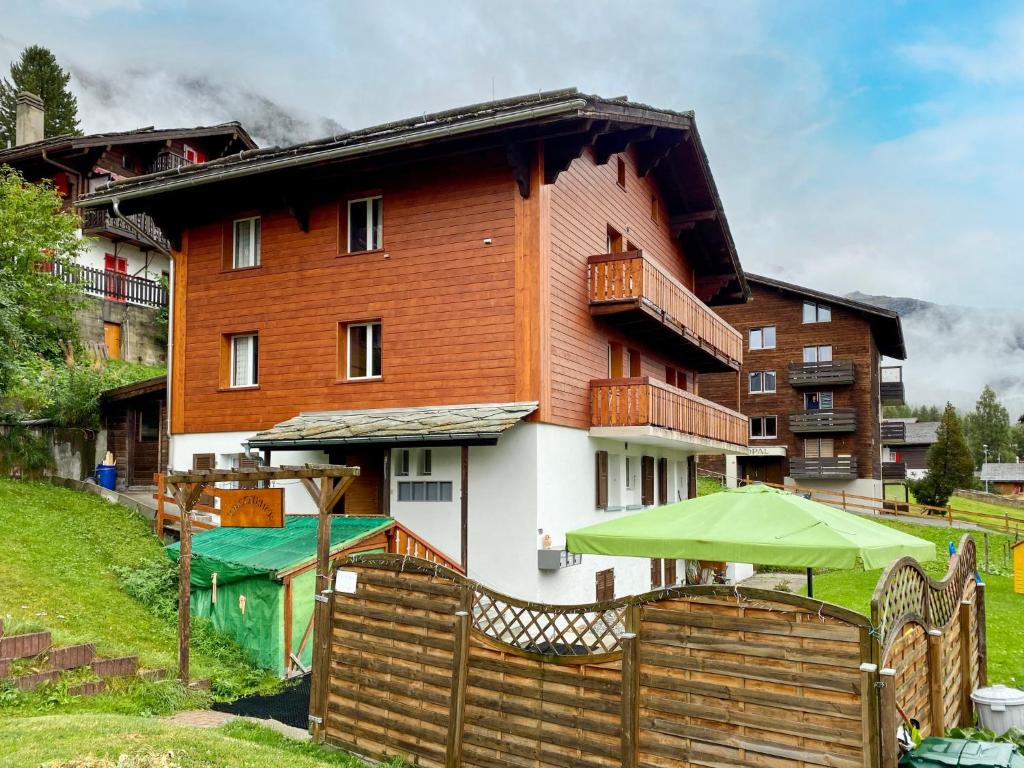 a house with a wooden fence and an umbrella at Apartment Chalet Jungtalblick- Wohnung Chilcheri by Interhome in Grächen