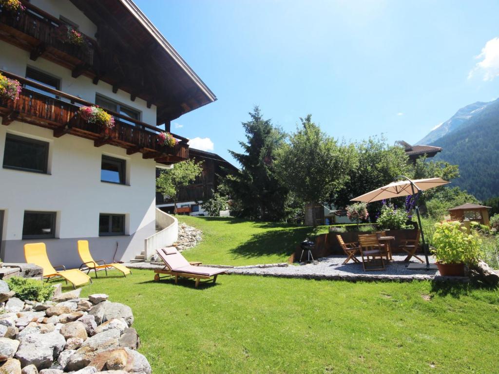 a yard with chairs and an umbrella and a building at Studio Stöcklhof-3 by Interhome in Pettneu am Arlberg