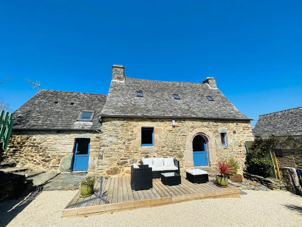 a stone house with a wooden deck in front of it at Le Penty in Guimaëc