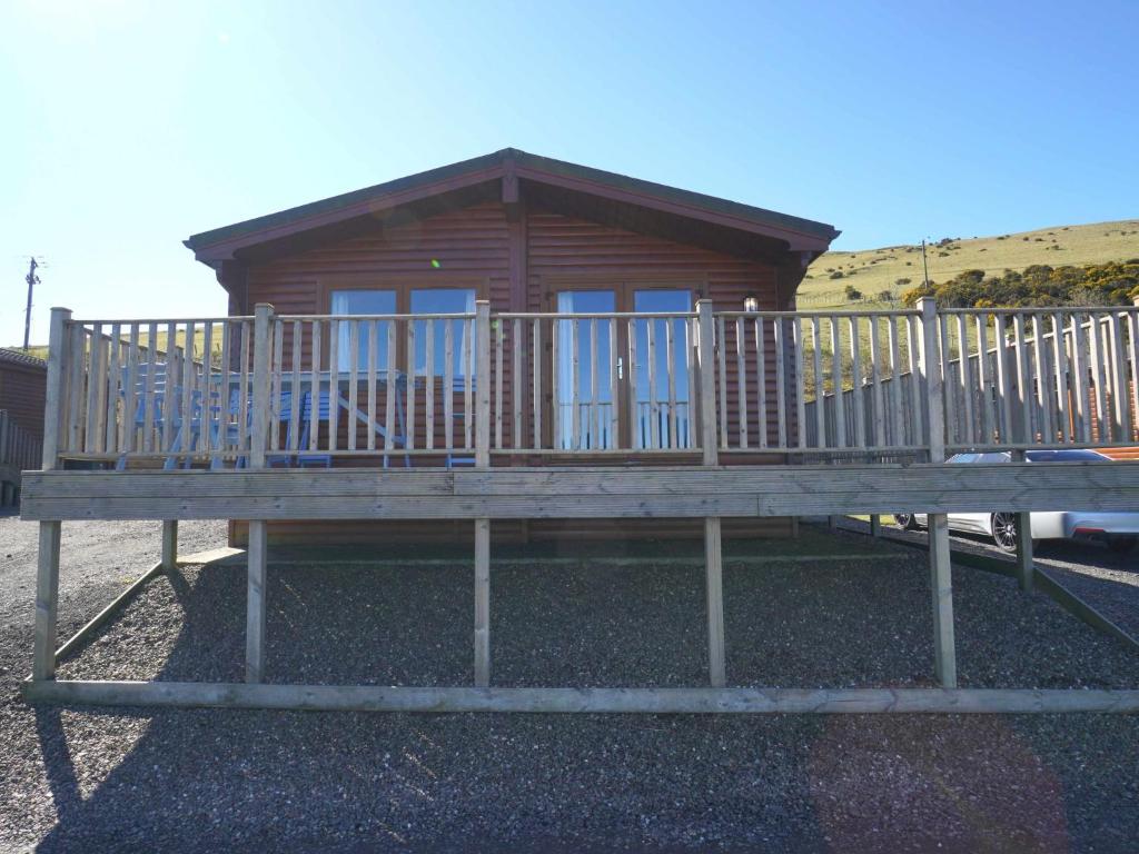 uma cabina de madeira com um grande deque em Chalet Loch Leven Lodge 11 by Interhome em Kinross