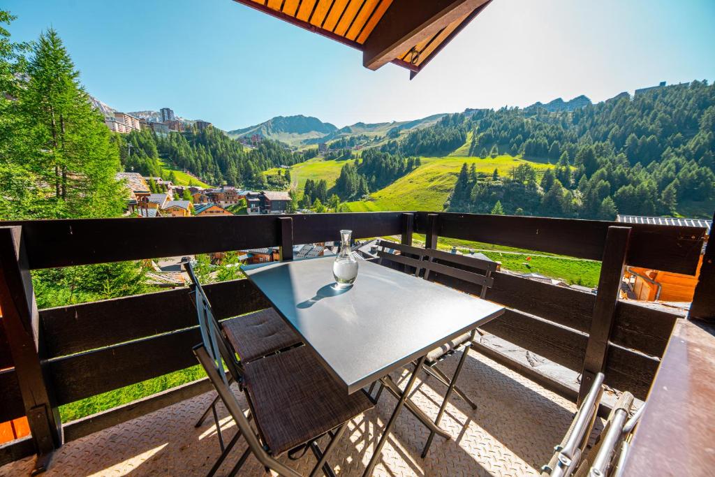 uma mesa e cadeiras numa varanda com vista em Le Panoramix em Plagne 1800