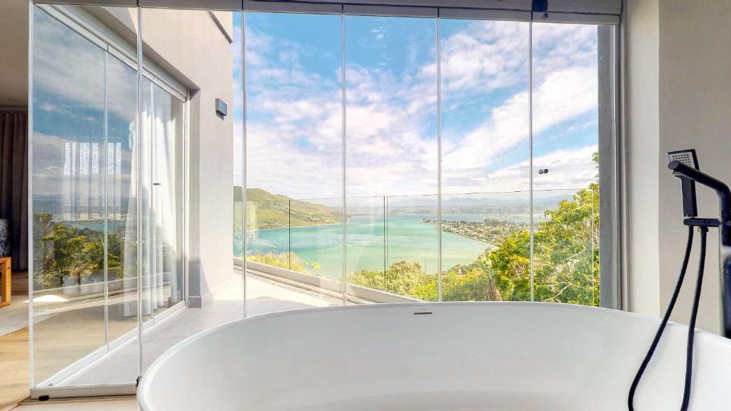 a bath tub in a room with a large window at 34@Paquita in Knysna