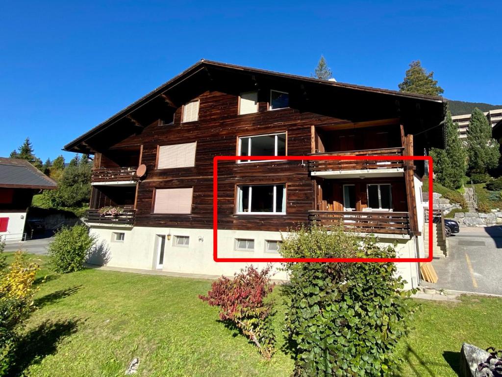Uma casa com uma caixa vermelha à frente. em Apartment SnowKaya Grindelwald by Interhome em Grindelwald