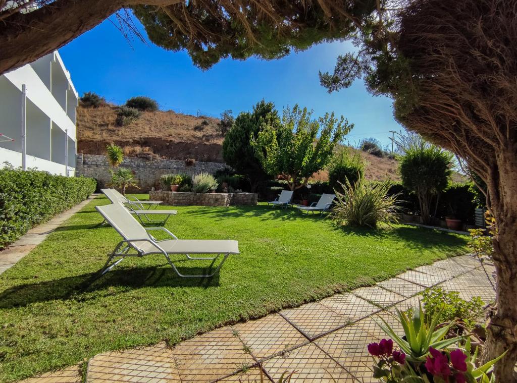 a white bench sitting in the grass in a yard at Mythos Apartments in Damnoni