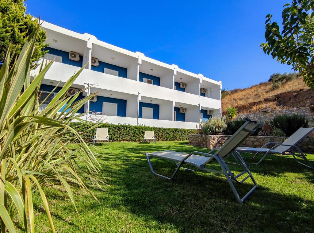 a building with two lawn chairs in front of it at Mythos Apartments in Damnoni