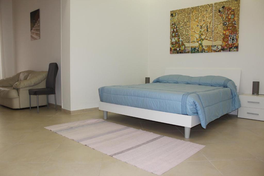 una camera con un letto, una sedia e un quadro di Agorà-Akrai B&B a Palazzolo Acreide