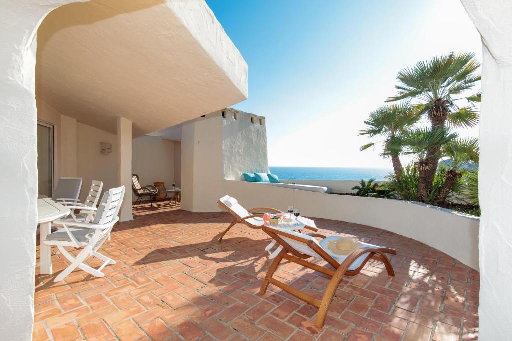 un patio avec une table et des chaises et l'océan dans l'établissement Sea View Duplex YourHostHelper, à Théoule-sur-Mer