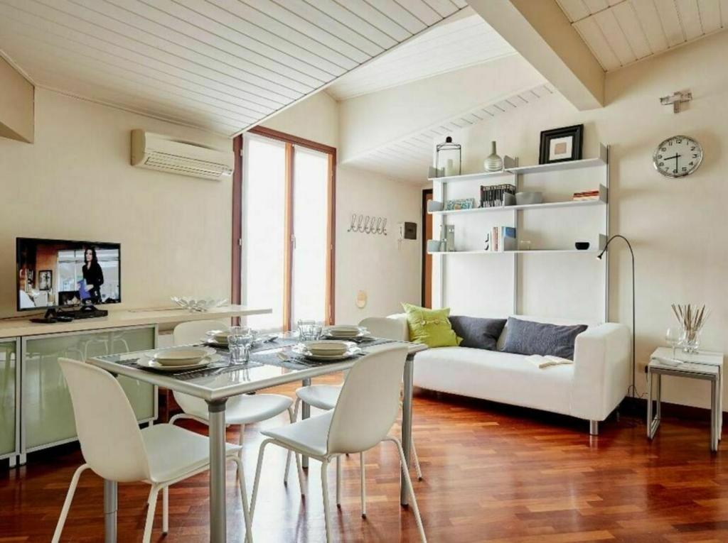 ein Wohnzimmer mit einem weißen Sofa, einem Tisch und Stühlen in der Unterkunft Settembrini in Mailand