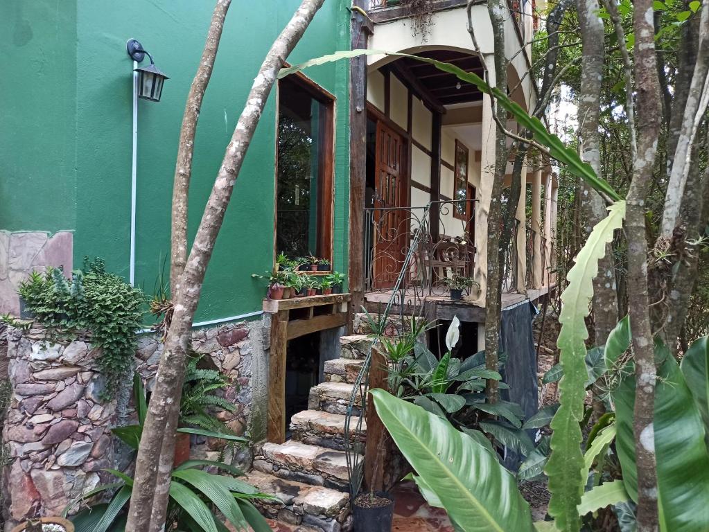 CASA DA MATA descanso e sossego na natureza في إيبوكوارا: مبنى أخضر مع سلالم تؤدي إلى باب