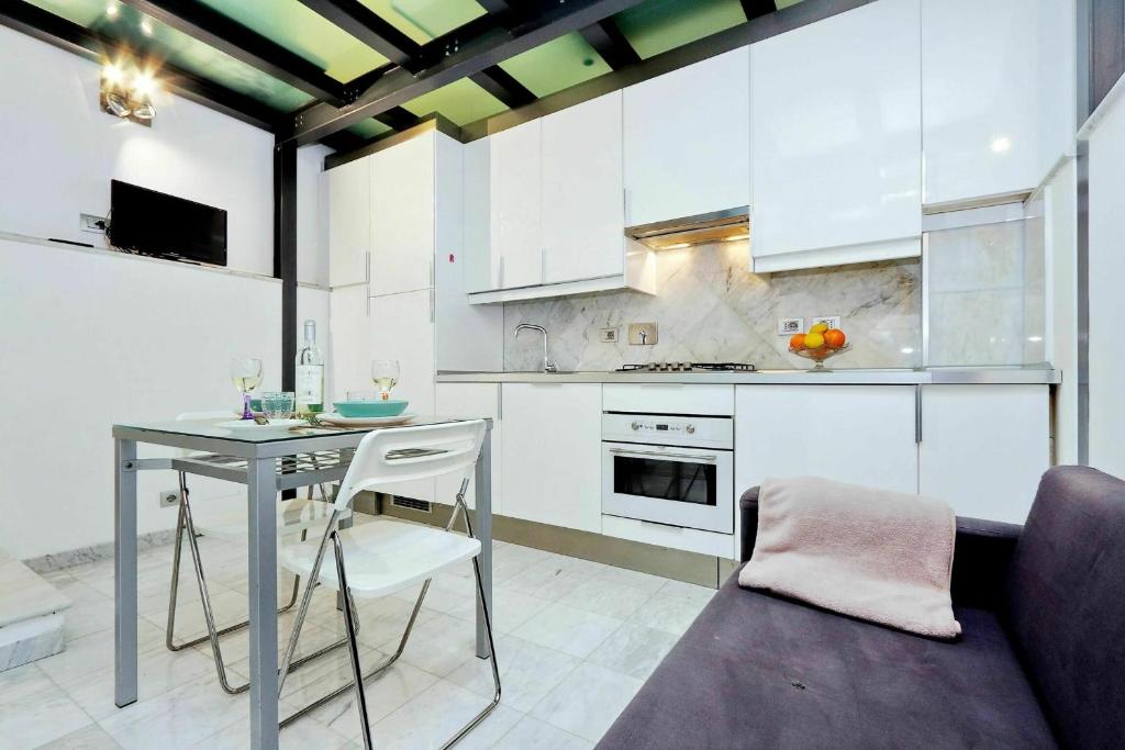 ローマにあるCoronariの白いキャビネット、テーブル、ソファ付きのキッチンが備わります。