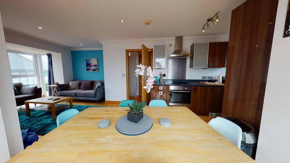 a kitchen and dining room with a wooden table and chairs at Cosy Town House Sleeps 8 in Pembroke Dock